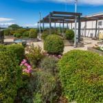 Garten mit Beeten, Sträuchern und Terrasse mit Blick auf die Landschaft.