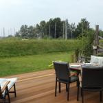 Deck with table and chairs, view of grassland and sailboats