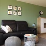 Black sofa with cushions, wall with pictures and wooden cabinet.