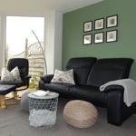 Living room with black leather sofa, seating area, and view to terrace.