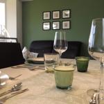 Dining table with dishes and glasses against green wall with pictures.