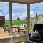 Large windows overlook a terrace with table and chairs. A black chair is in the foreground.