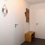 Eingangsbereich mit Holzbank, Wandgarderobe und Willkommensschild.