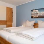 Schlafzimmer mit Doppelbett, Holzmöbel und Wandbild