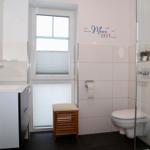 Badezimmer mit Waschbecken, Toilette und Dusche. Fenster mit Jalousie.