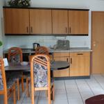 Küche mit Esstisch, Holzschränken und Fliesenboden.