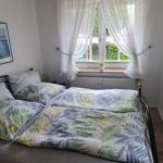 Schlafzimmer mit Doppelbett, Fenster und weißen Vorhängen.