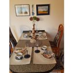 Gestellte Tischdecke mit Tassen, Gläsern und Blumen auf Tisch