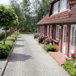 Gepflasterter Weg führt an roten Backsteinhäuser mit weißen Türen und Blumenbeeten vorbei.