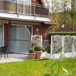 Haus mit Balkon, Terrasse und Garten mit weißen Lattenzaun.