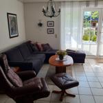 Wohnzimmer mit Sofa, Sessel und TV-Möbel. Durchgang zur Terrasse.