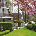 Haus mit Balkon, Garten und blühendem Baum im Vordergrund.