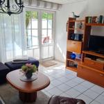 Wohnzimmer mit Sofa, Couchtisch und TV-Möbel. Durchgang zum Garten.