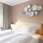 Schlafzimmer mit Bett, Wanddekoration und Nachttisch mit Lampe.