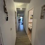Hallway with bedroom and view into living area with window.