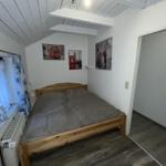 Bedroom with wooden bed, wall art, and window with curtains.