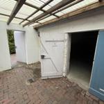 Backyard with gate, garage door, and roof structure of wood and glass.