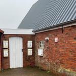 Red brick building with white mailboxes and sloped metal roof.