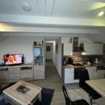 Living kitchen with TV, dining table, and modern kitchen unit.