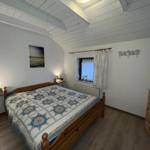 Bedroom with wooden bed, window, and dresser.