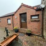 Red brick building with entrance door and plants in the garden.