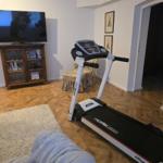 Vaulted room with treadmill, TV, and wooden floor