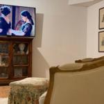 A living room with a TV, a wooden cabinet, and two armchairs.