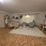 Living room with wooden floor, sofa, armchairs, and dining table