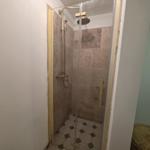 Shower with glass enclosure, stone tiles, and showerhead