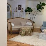 A living room with sofa, armchair, and plant on wooden floor.