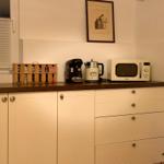 Kitchen counter with refrigerator, microwave, and coffee machine.