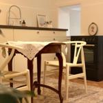 Dining table with chairs in front of kitchen with stove and sink.