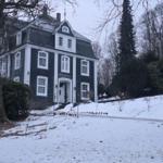 Manor-style house with white plaster and dark slate roof in the snow.