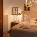 Bedroom with bed, nightstand, chandelier, and wooden wardrobes.