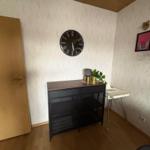 Entrance area with cabinet, clock, and plants on the wall.