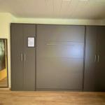 Bedroom with integrated wardrobe and mirror on the wall.