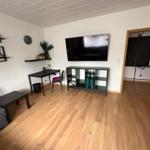 Living room with sofa, TV, desk, and wooden floor.
