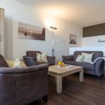 Wohnzimmer mit Sofa, Sessel und Tisch. Hintergrundbild an der Wand.