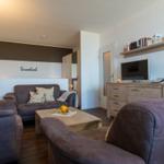 Wohnzimmer mit Sofa, Couchtisch und Fernseher. Wand mit Schriftzug Traumland.