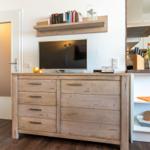 TV auf Holzschrank, Küchenbereich mit Blumen und Kochutensilien