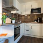 Küche mit weißen Schränken, Holzoberfläche und integriertem Herd.