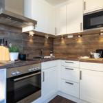 Küche mit weißen Schränken, Holzoberfläche und Bosch-Geräten.