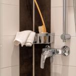 Dusche mit Duschbrause, Handtuch und Bürste an der Wand
