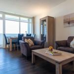 Wohnzimmer mit zwei Sesseln, Tisch und Blick auf Balkon.