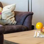 Ein braunes Sofa mit Kissen und Obst auf einem Tisch.