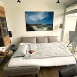 Schlafzimmer mit Bett, Wandbild und Balkonzugang.