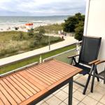 Terrasse mit Tisch und Stühlen. Blick auf Strand und Meer.