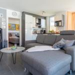 Wohnbereich mit Sofa, Kamin und Küche im Hintergrund.