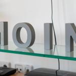 Glasregal mit grauen Buchstaben MOIN und Steckdosen darunter