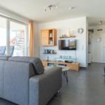 Wohnzimmer mit Sofa, TV und Balkonzugang.